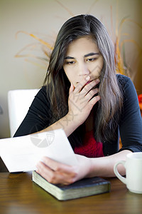 少女或年轻女性在阅读留言 担忧的言语笔记学习混血儿卡片长发混血女童女士眉头桌子图片