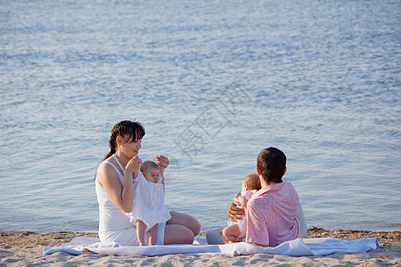 家庭在海滩上母亲蓝色假期生活微笑育儿双胞胎母性拥抱童年图片