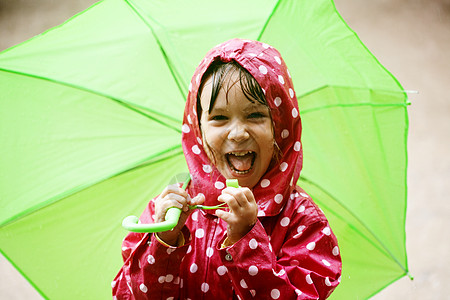 小女孩在雨中行走雨衣孩子雨滴育儿下雨微笑女孩红色水坑喜悦图片