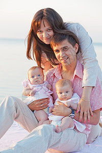 家庭母性父母婴儿拥抱父亲双胞胎孩子们女孩们育儿海滩图片