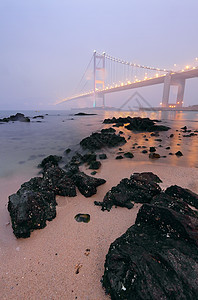 在沙滩和大桥上 有岩石 薄雾中图片