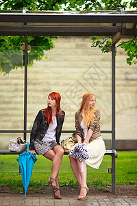 巴士站两个女孩裙子高跟鞋快乐讲话金发卷曲照片公共汽车乘客玻璃图片