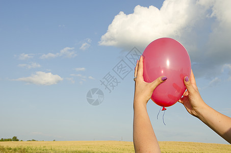 女性手握红色气球背景天空场图片
