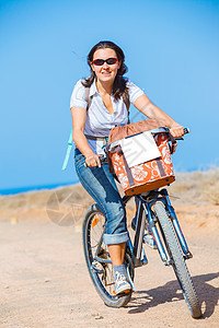 在户外骑自行车的妇女微笑着闲暇相机享受黄色女孩们海滨蓝色一代女士乐趣图片