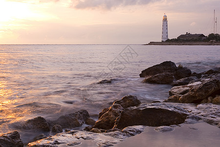 日落时的美丽的岩石海滨沙滩 有灯塔指导建筑安全蓝色海滩警告地标海岸海岸线海浪图片