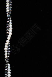 黑色天鹅绒上的白珍珠和黑珍珠作为背景图片