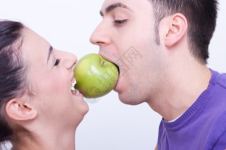双唇间有绿苹果的年轻夫妇幸福男人喜悦家庭黑发食物女孩男朋友微笑水果图片