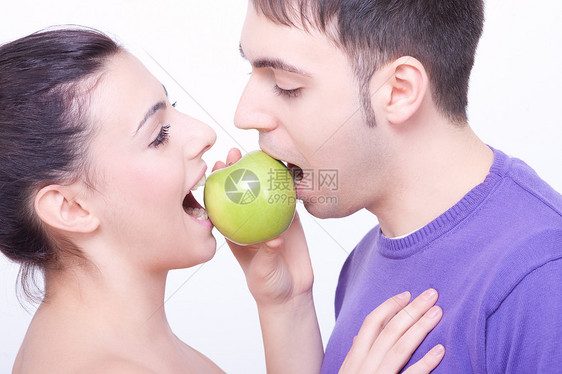 双唇间有绿苹果的年轻夫妇乐趣水果女士女孩黑发男朋友女性食物家庭女朋友图片