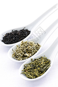 将干茶叶组合成勺子酿造黑色饮料福利叶子绿色宏观白色背景图片