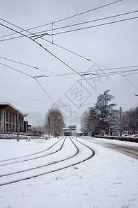 雪层覆盖的铁轨街道运输电缆电车平行线场景基础设施建筑天气美丽图片