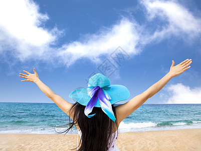 年轻女子在海滩举起手来图片