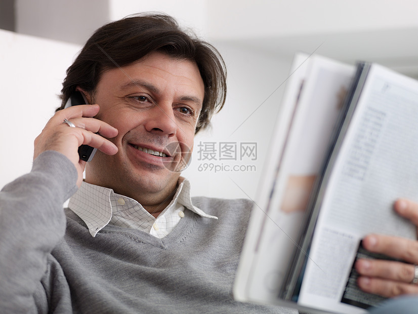 快乐的男人用电话从目录中购买图片