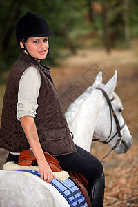 年轻女子骑着美丽的白马图片