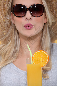 有橙汁的女人玻璃女性白色稻草果汁帽子金发头发太阳镜太阳图片