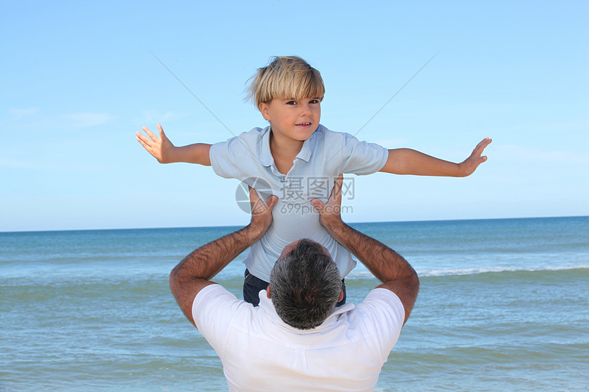 父亲带着儿子在沙滩边图片