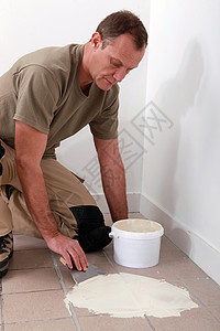 男人在旧地板砖上散布粘合剂建造维修改造吊具瓷砖装修房子传播建设者整容图片
