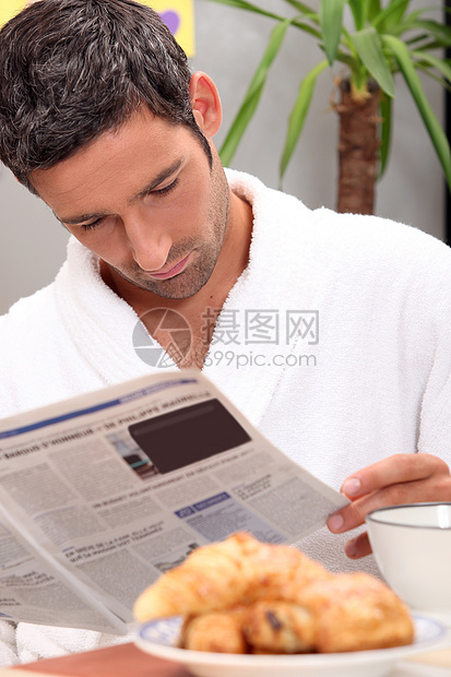 男人在早餐时看日记公告阅读杂志厨房羊角出版物小册子报纸浴衣糕点图片