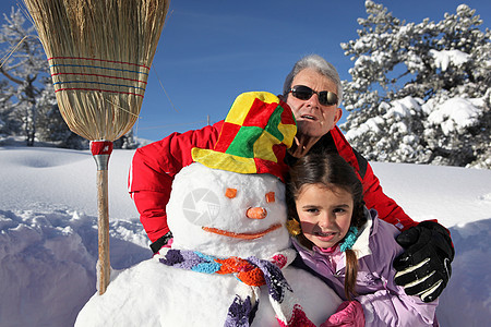 父亲和女儿与雪人帽子爸爸女孩太阳镜祖父季节童年拥抱女性回忆图片