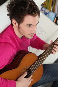 年轻男人在家里弹吉他图片
