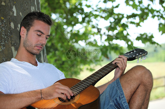 在树下弹吉他的人图片