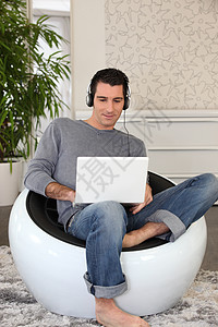 通过笔记本电脑收听音乐的人歌曲技术赤脚爱好白色长椅享受工作幸福沙发图片