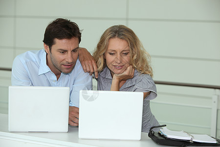 两人在笔记本电脑上工作专注丈夫思维男人棕色个人妻子头发金发女性图片