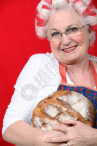 头发有卷卷卷发的老太太 拿着新鲜烤面包图片