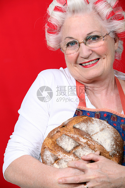 头发有卷卷卷发的老太太 拿着新鲜烤面包图片