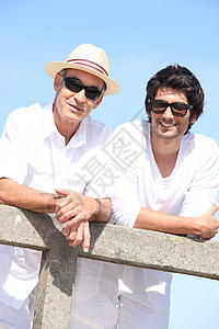 两个穿白衣服的男人 仰着蓝色天空背景的栅栏背景图片