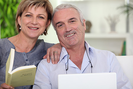 情侣在沙发上放松电脑微笑妻子水平丈夫男性亲热女士拥抱报纸图片