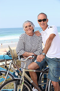 高级夫妇在沙滩骑自行车图片