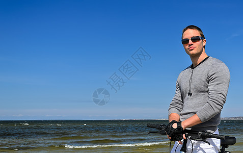 海边骑自行车的英俊男子肖像男人假期海岸冒险活动海洋海滩运动旅行天空图片