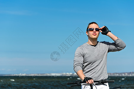 海边骑自行车的英俊男子肖像男人支撑旅行海岸假期男性海滩冒险海洋运动图片