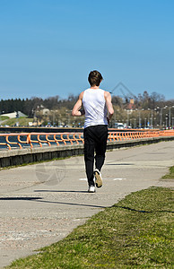 年轻的运动男性在海岸线上奔跑 从后面图片