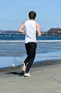 年轻的运动男性在海滩上奔跑 从后面图片