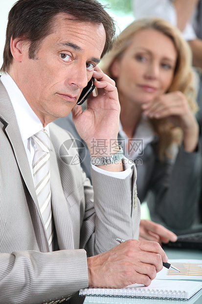 会议期间使用手机的男执行官图片
