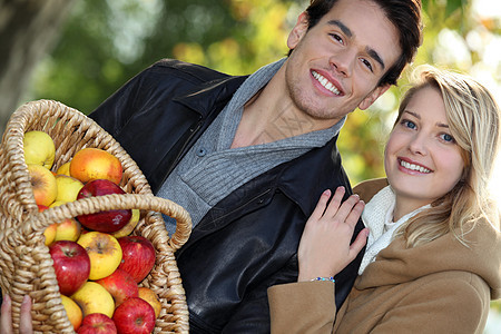 年轻夫妇的笑容都充满了一篮子苹果图片
