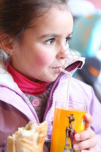 小女孩喝橘子汁 用稻草背景图片