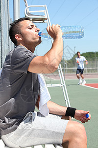 网网球法庭边线上的人类饮用水图片
