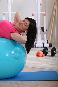 年轻女子在健身房锻炼稳定球腹部运动图片
