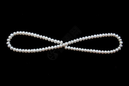 黑色丝绸上的白珍珠作为背景展示首饰光泽度反射象牙珠子项链奢华婚礼细绳图片