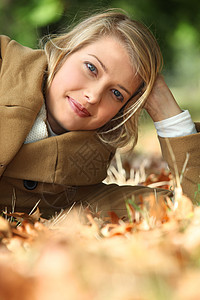 妇女躺在地上蓝色女性林地树叶头发金发树木眼睛白色成人图片