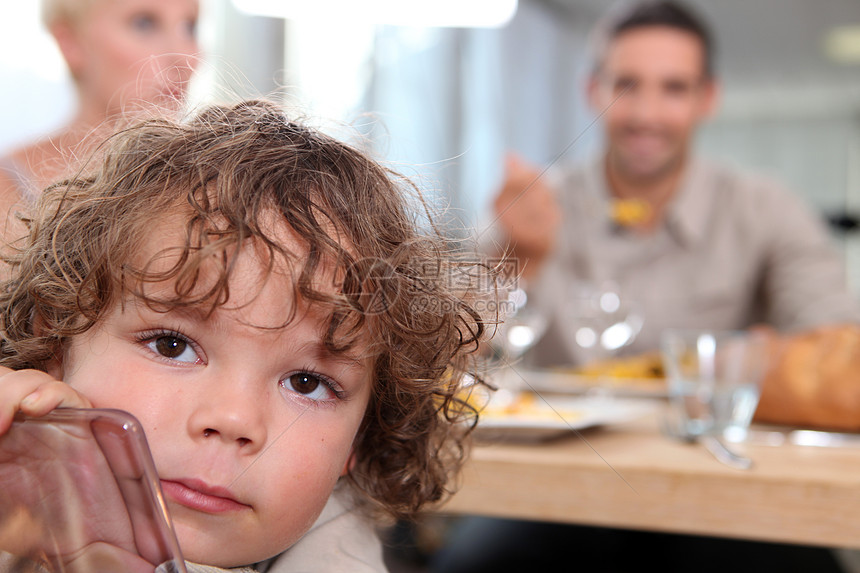 小男孩与有背景的父母一起坐在桌边的小孩图片