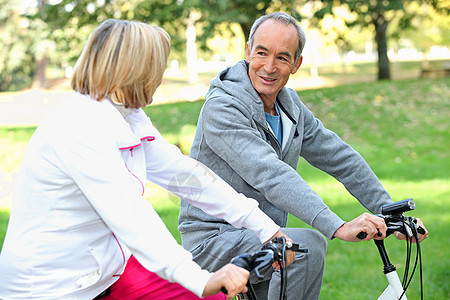 骑自行车的老年夫妇培训师运动服人员公园闲暇帽衫夫妻训练晴天女性图片