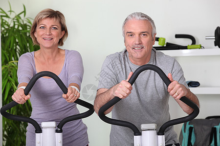 健身房的高级夫妇骑自行车图片