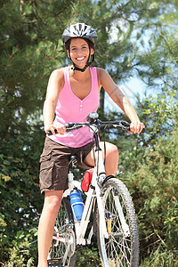 妇女在森林中骑自行车头盔乐趣女孩父母踪迹树木微笑闲暇女性运动图片