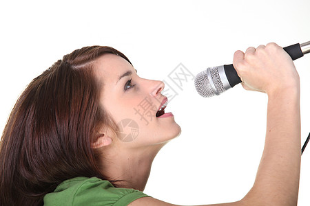 一个年轻女子唱到麦克风的演播室镜头图片