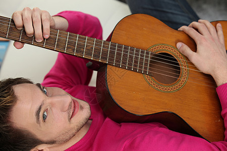 弹声吉他的人娱乐享受沙发微笑学习男性成人音乐家唱歌练习图片