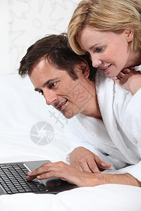 在笔记本电脑上的情侣 穿礼服微笑丈夫敷料白色夫妻金发妻子文件浴衣男性图片