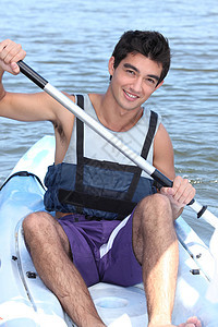 黑头发男孩在独木舟中划船图片